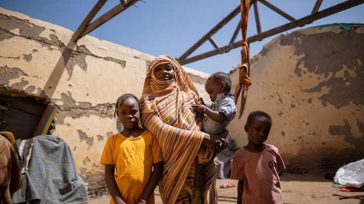Altuma stands in her temporary house with her three children.