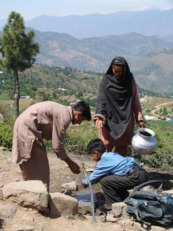 Woman and children retrieving water from a spring fountain.
