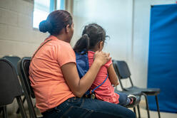 The backs of a mother holding her daughter.