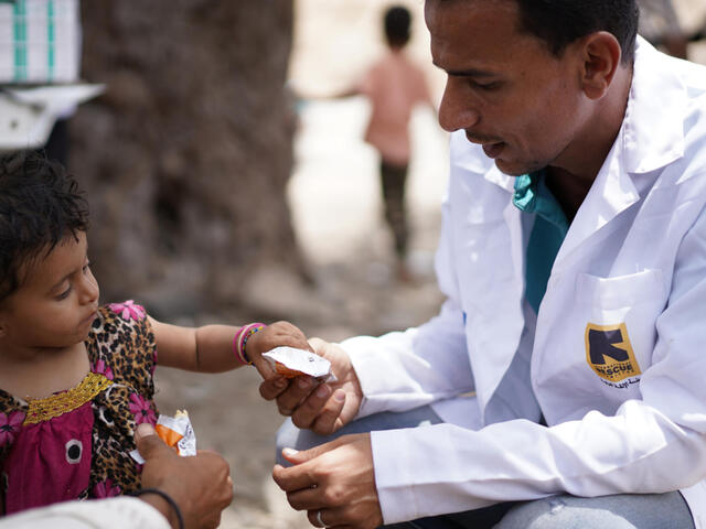 Little girl being handed a nutrition pack from man in a white coat