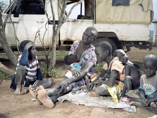 Joyce with her five children, aged four months — 10 years, waiting to have their scant belongings searched before they can enter the transit site. 