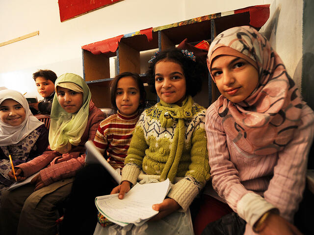 Six Syrian refugee children sit in a row,