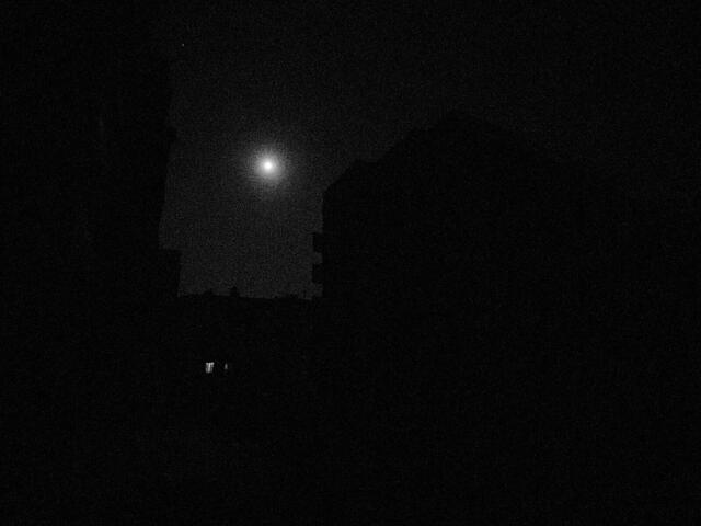 The city is pitch black apart from light from the moon. 
