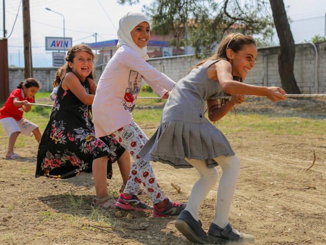 Syrian children living in a refugee camp in Greece play tug of war