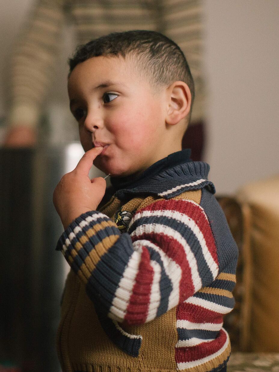 Hudaifah's four-year-old son, Bilal, eating honey from his finger.
