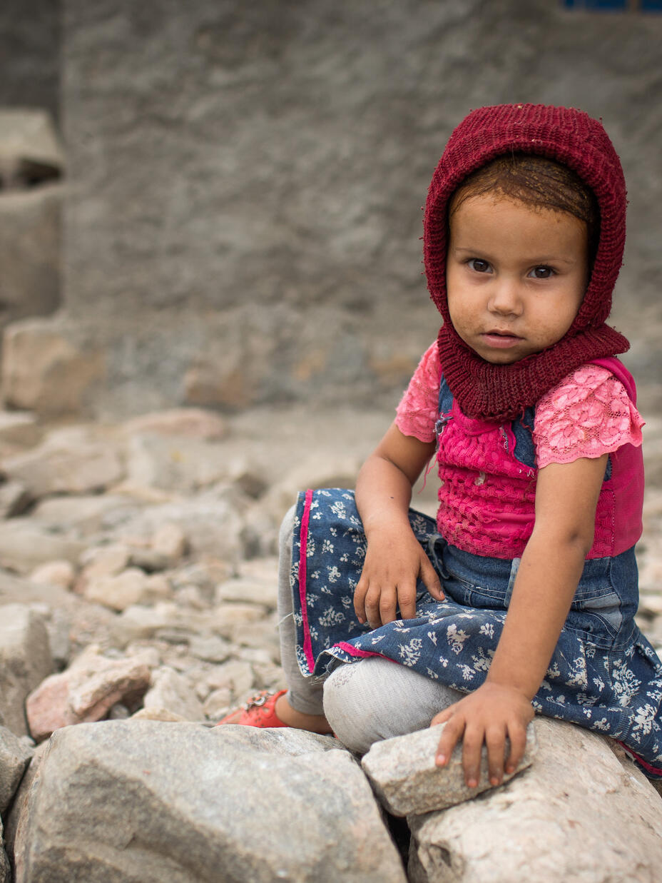 A young girl sits on the ground in a village in Yemen