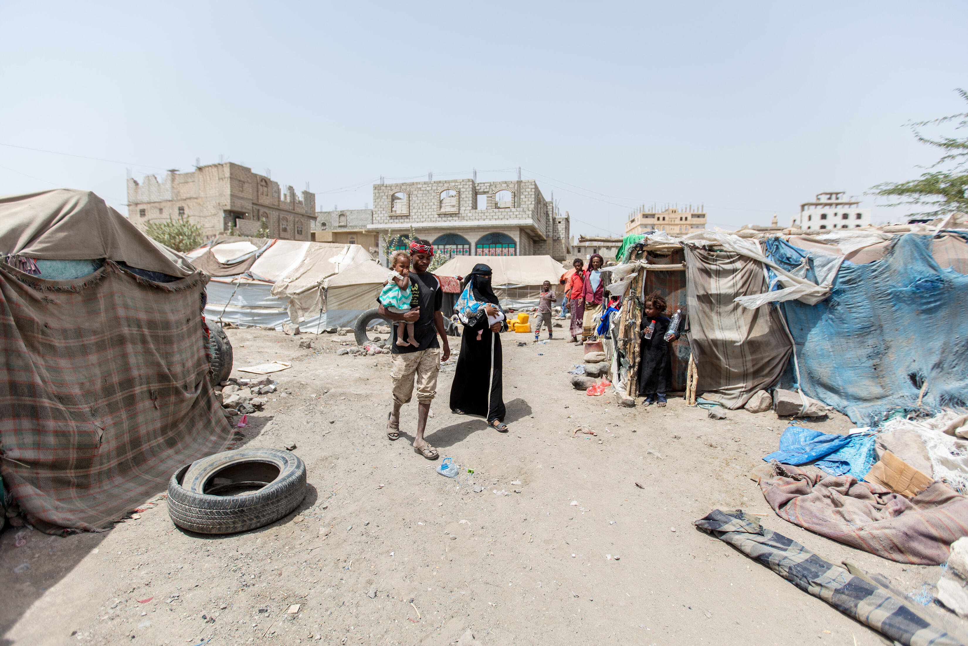 A family walk through a camp in Yemen.