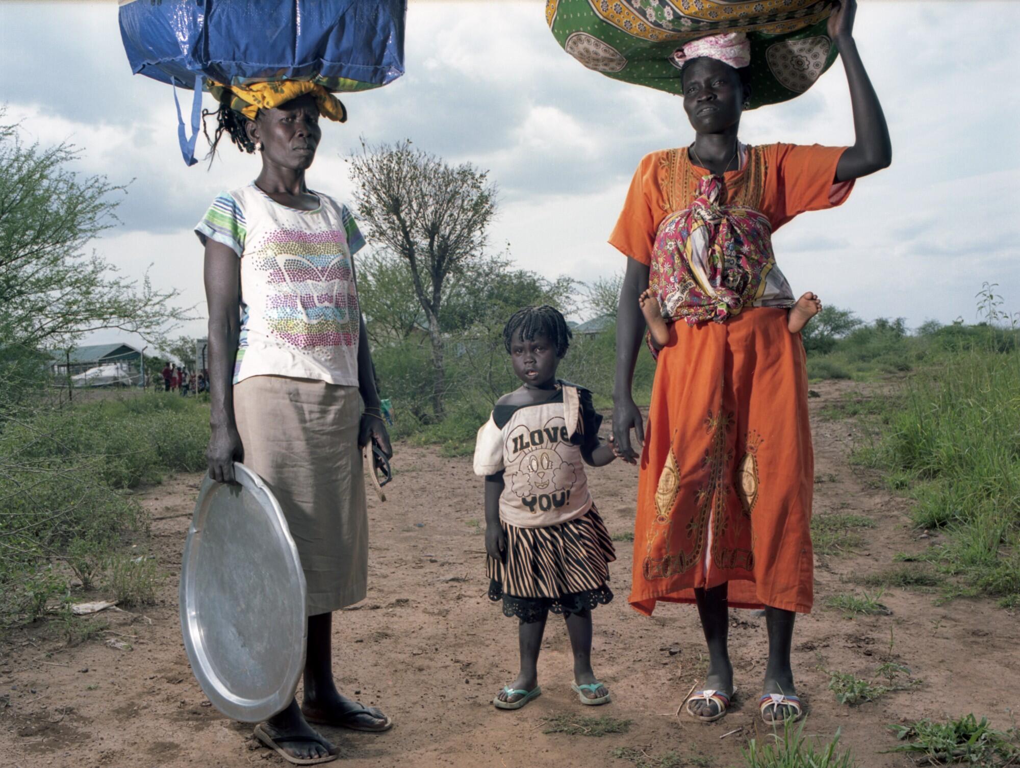 Women and children forced to flee their homes in South Sudan arrive at the Kenyan border on foot carrying their belongings.