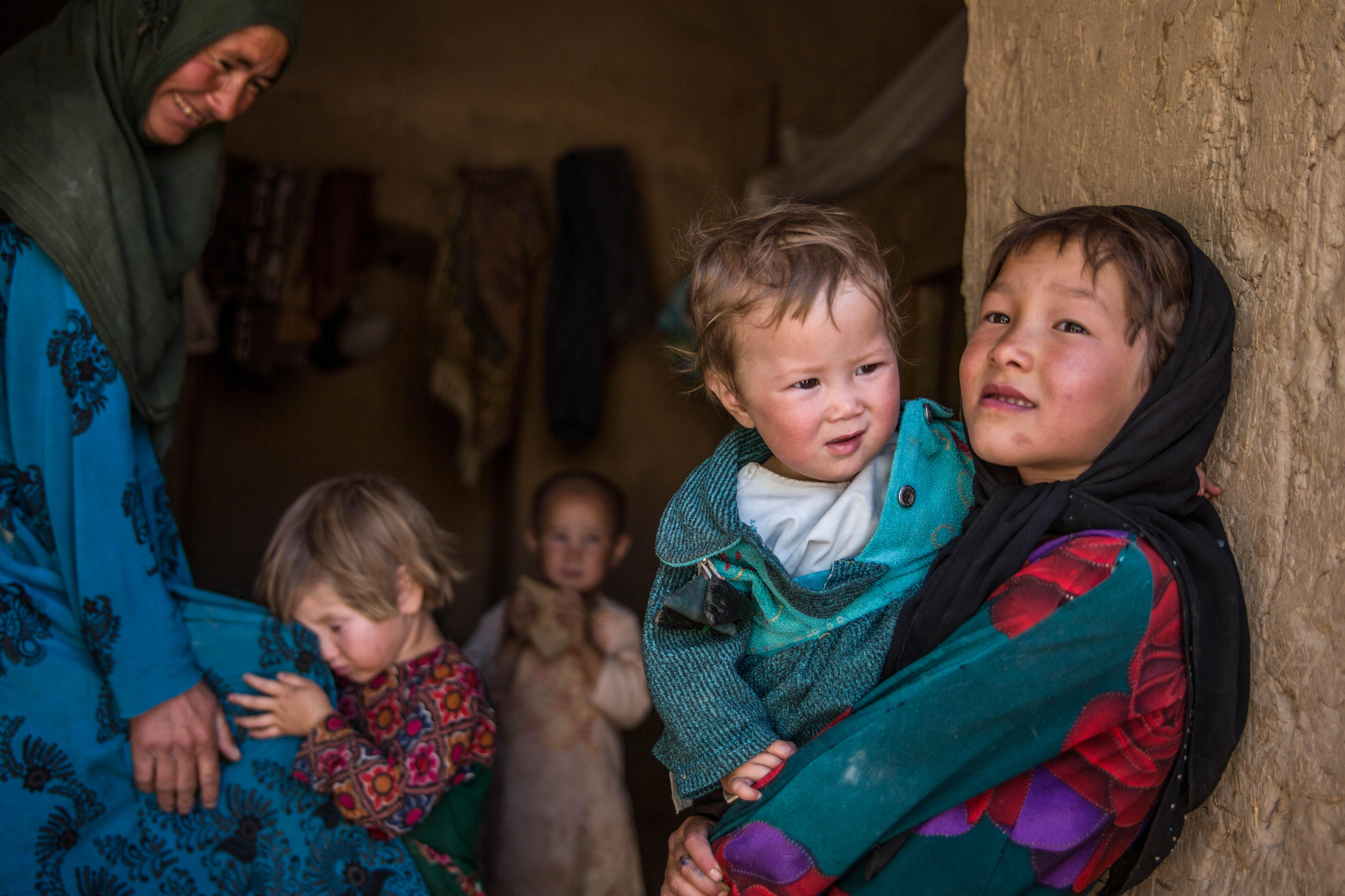 Young Afghan children stand in a doorway.