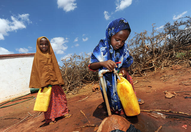 Two children fetching water at an IRC-installed water tap in Darussalam village, Galmudug state.