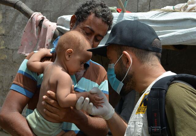 Thabit and his son with an IRC mobile health worker in Yemen 