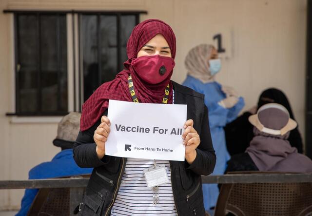 IRC nurse holds "Vaccines for All" sign in Jordan