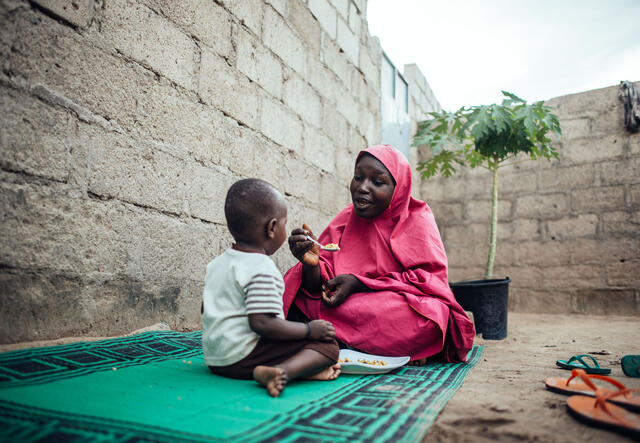 IRC client Bilkisu feeds her son at their home in Maiduguri, Borno, Nigeria.