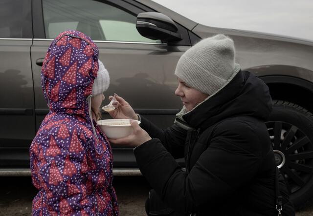 A women feeding a child with a spoon 