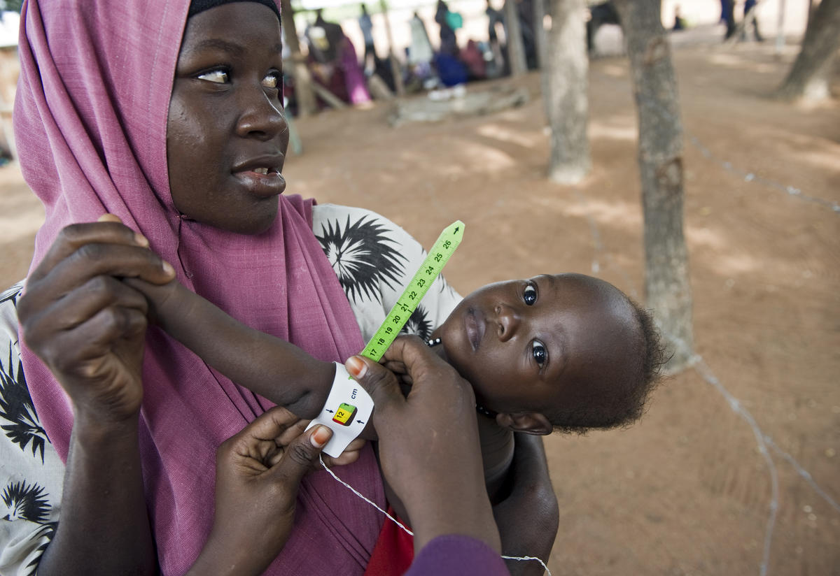 Infant doctor appointment Mother holds child in displacement camp while undergoing medical tests