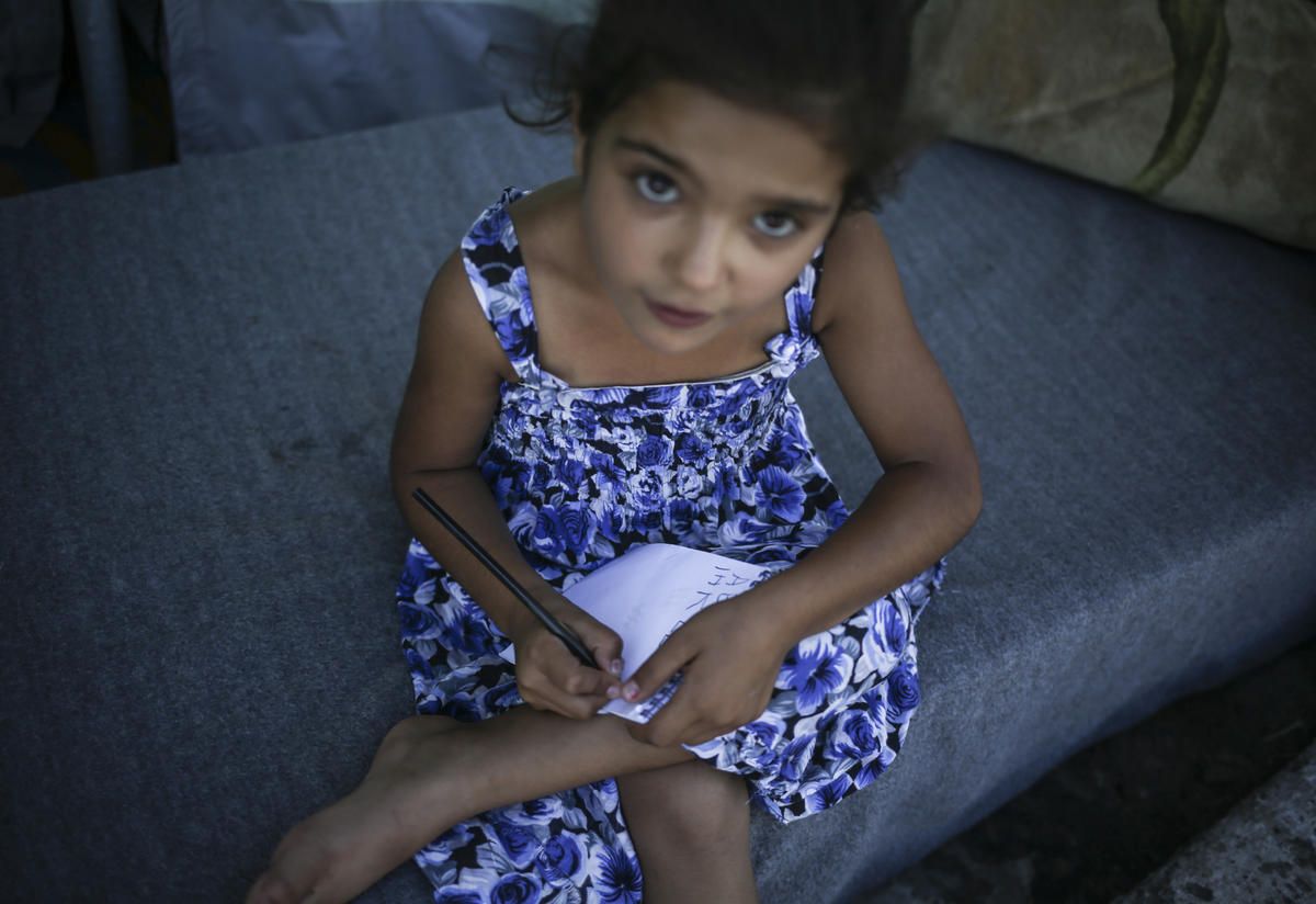 7-year-old writes in her notebook outside a tent 7-year-old writes in her notebook outside a tent