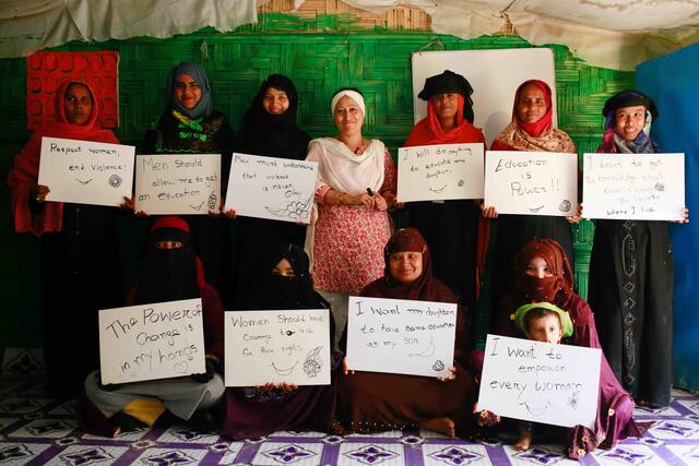 Activist and lawyer Razia Sultana stands with women holding handwritten signs at her women’s centre in Ukhiya camp, Cox's Bazar.