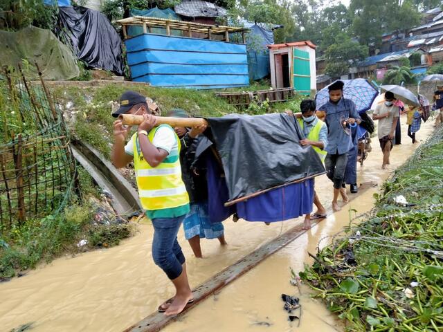 IRC emergency referral unit volunteers carry a patient to a nearby health facility following severe flooding in Cox's Bazar, Bangladesh.