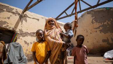 March 26, 2024 - Gedaref, Sudan. Altuma (45), and her children stand inside their roofless shelter.