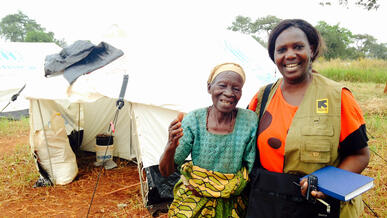 IRC workers poses for photo with elderly Burundian woman in front of tent in Nyaragusu refugee camp in Tanzania.